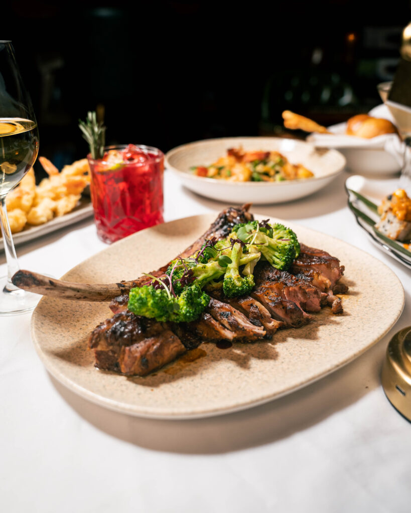 A plate of Steak with prawns, salad and a glass of cocktail on a table at The Library Lagos